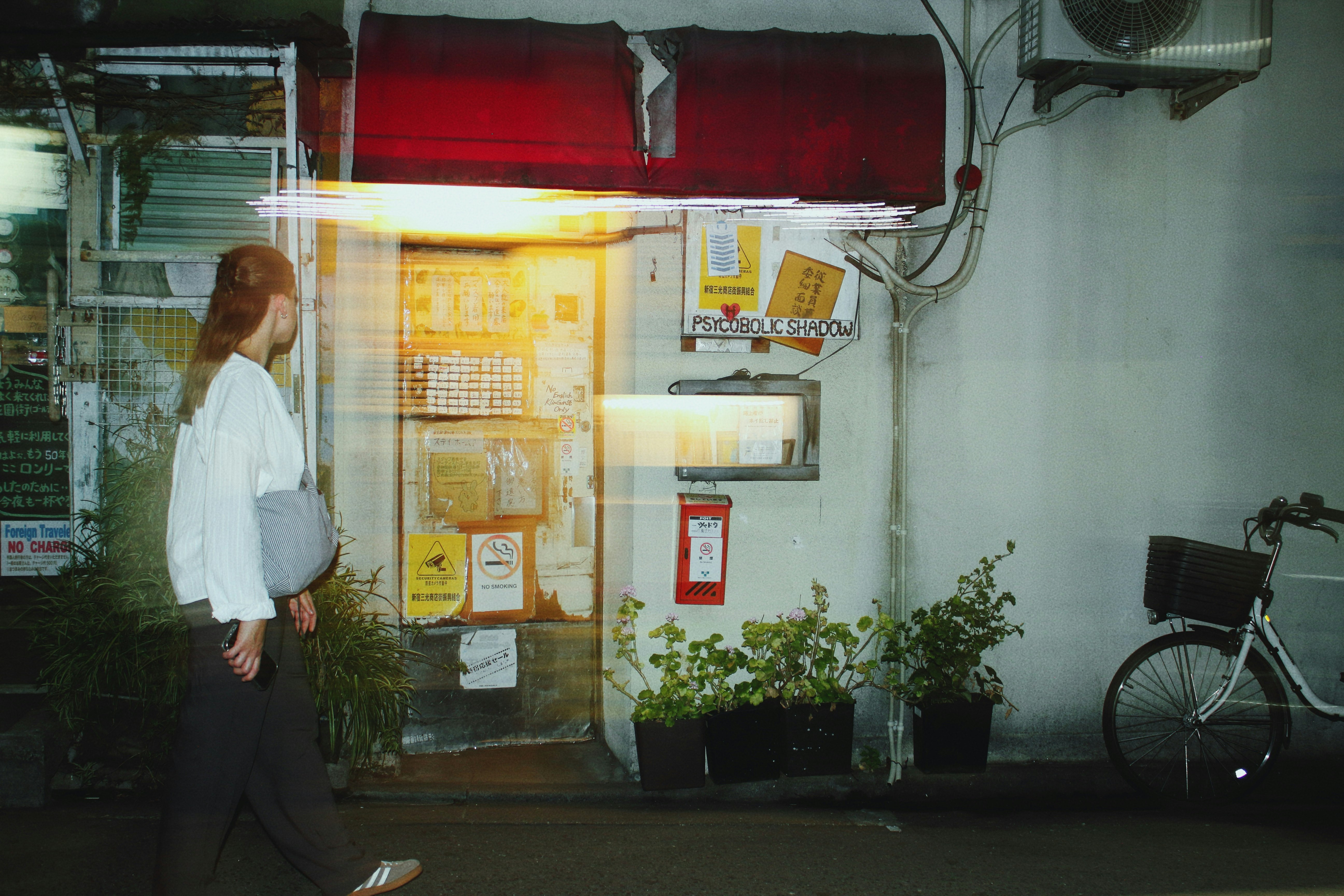 路地の壁に掲示物と自転車がある商店街の軒先