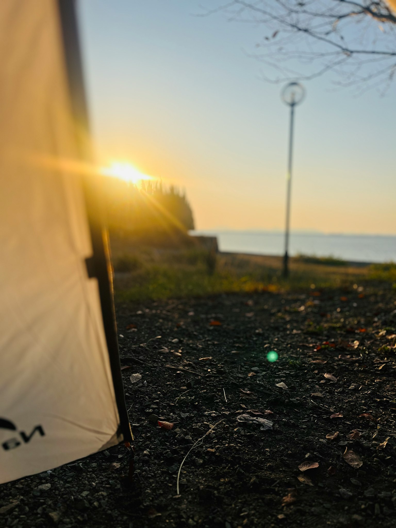 Tent side view with sunset over the sea and grassy area