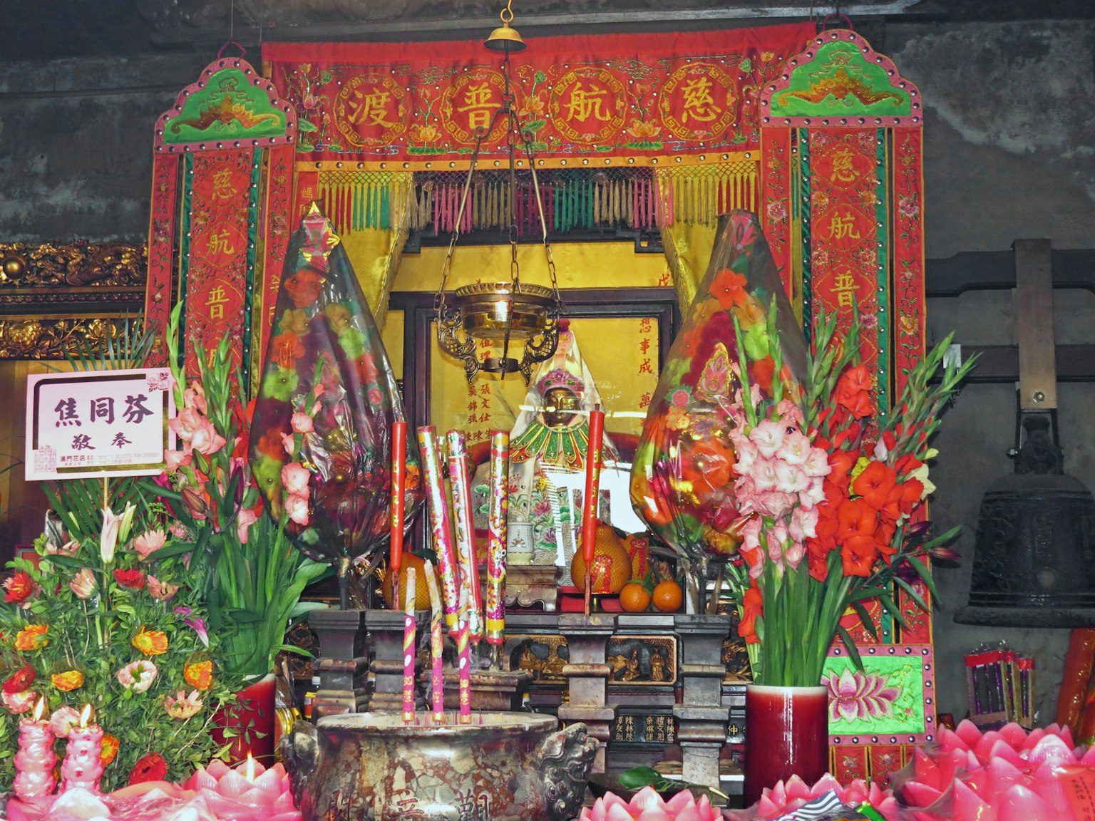 一個生動的祭壇，裝飾著鮮花和香，在神像前面