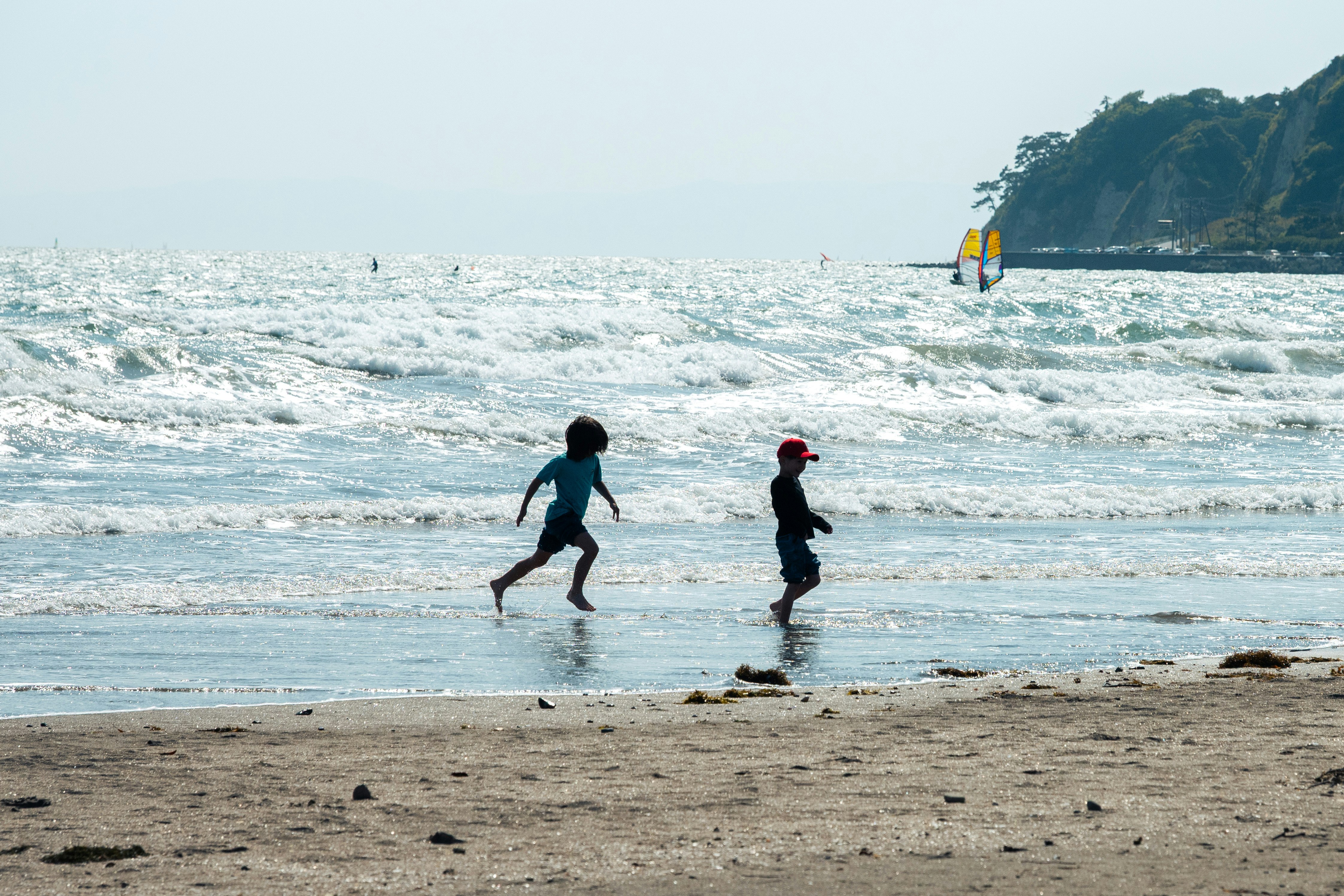 波打ち際を走る人々と海岸の景色