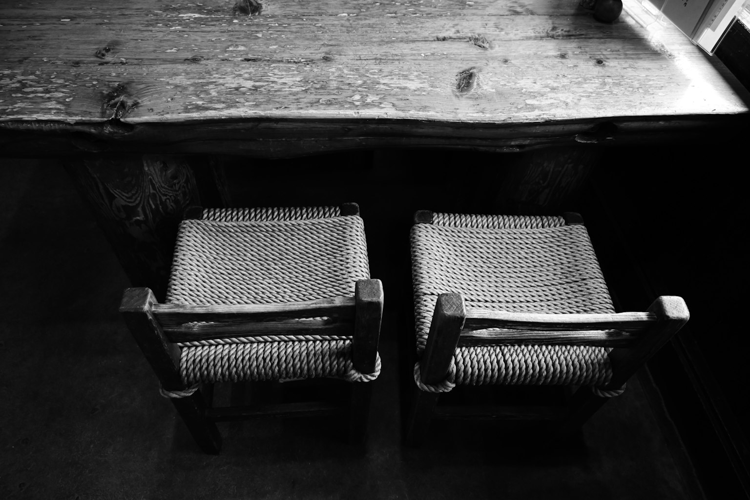A serene room featuring a wooden table and two woven chairs in black and white