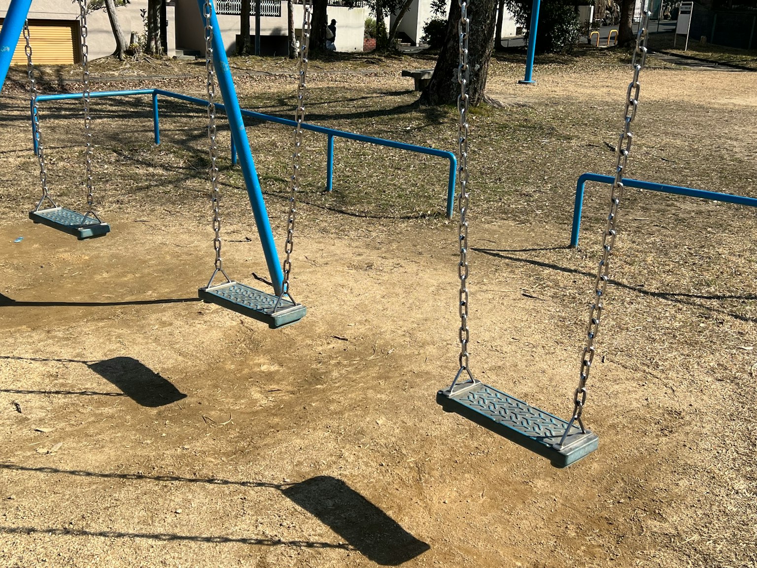 空蕩蕩的遊樂場裡的藍色秋千和沙地