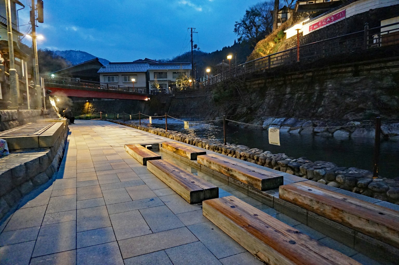 Panchine in legno lungo una passeggiata sul fiume in una città termale notturna