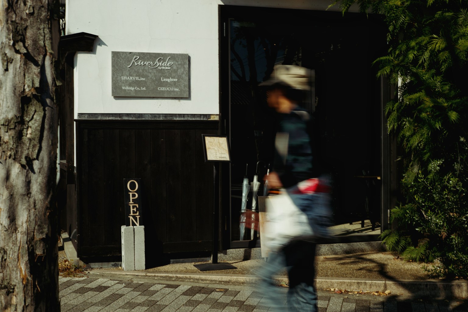 Cafe exterior with an open sign and a person walking by
