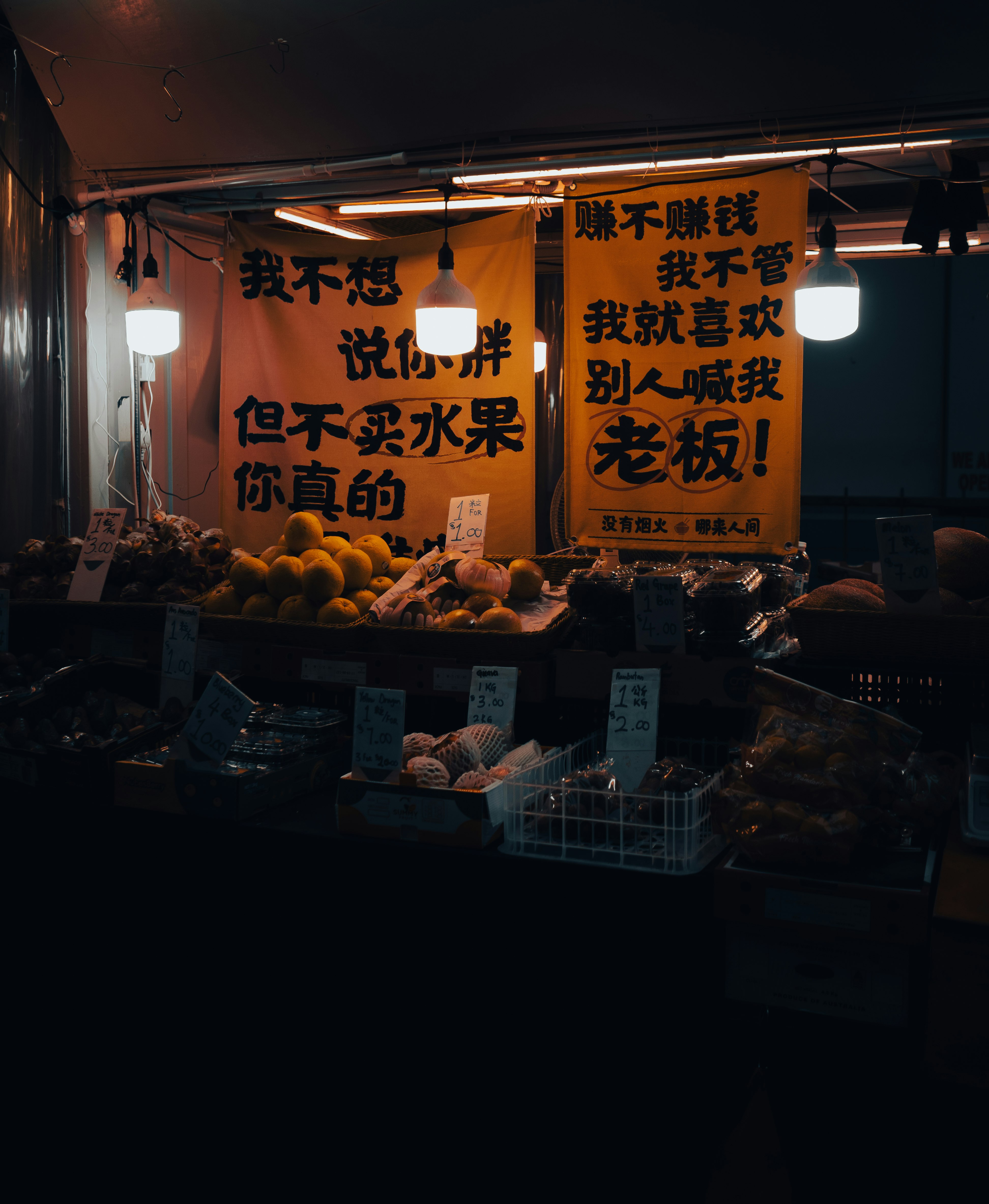 屋台の果物売り場と中国語の看板が並ぶ夜の街角