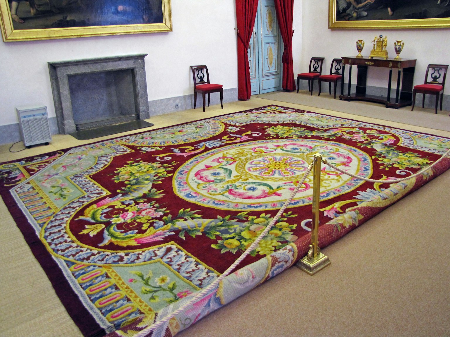 Interior de una habitación con una lujosa alfombra decorada cortinas rojas y pinturas de fondo