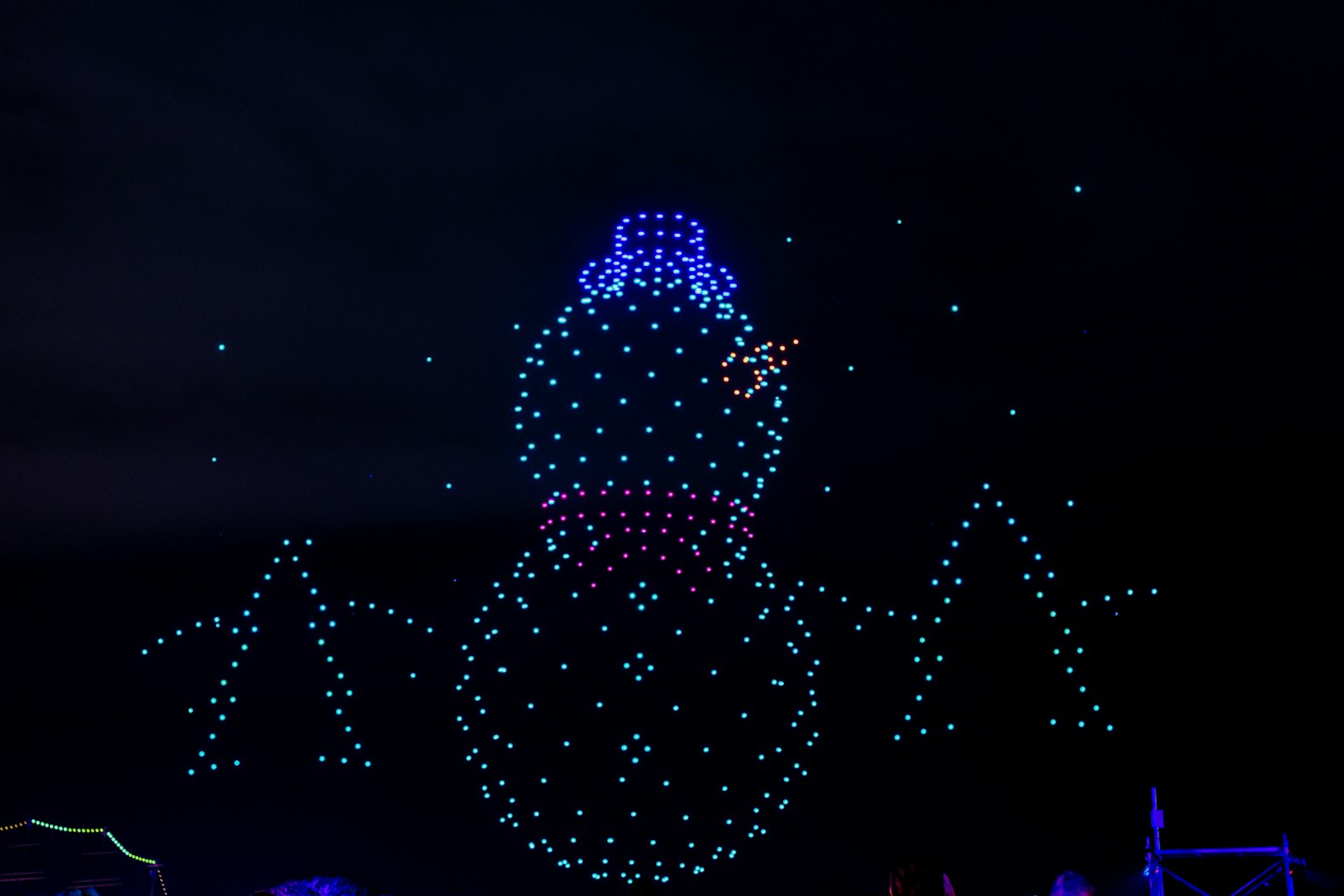 Pupazzo di neve illuminato con un cappello blu che brilla su uno sfondo scuro