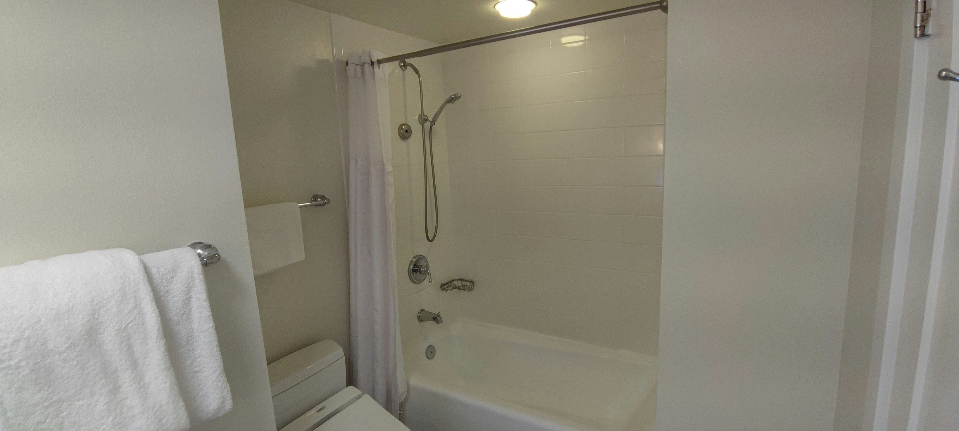 bañera de baño limpia con ducha y puerta de vidrio