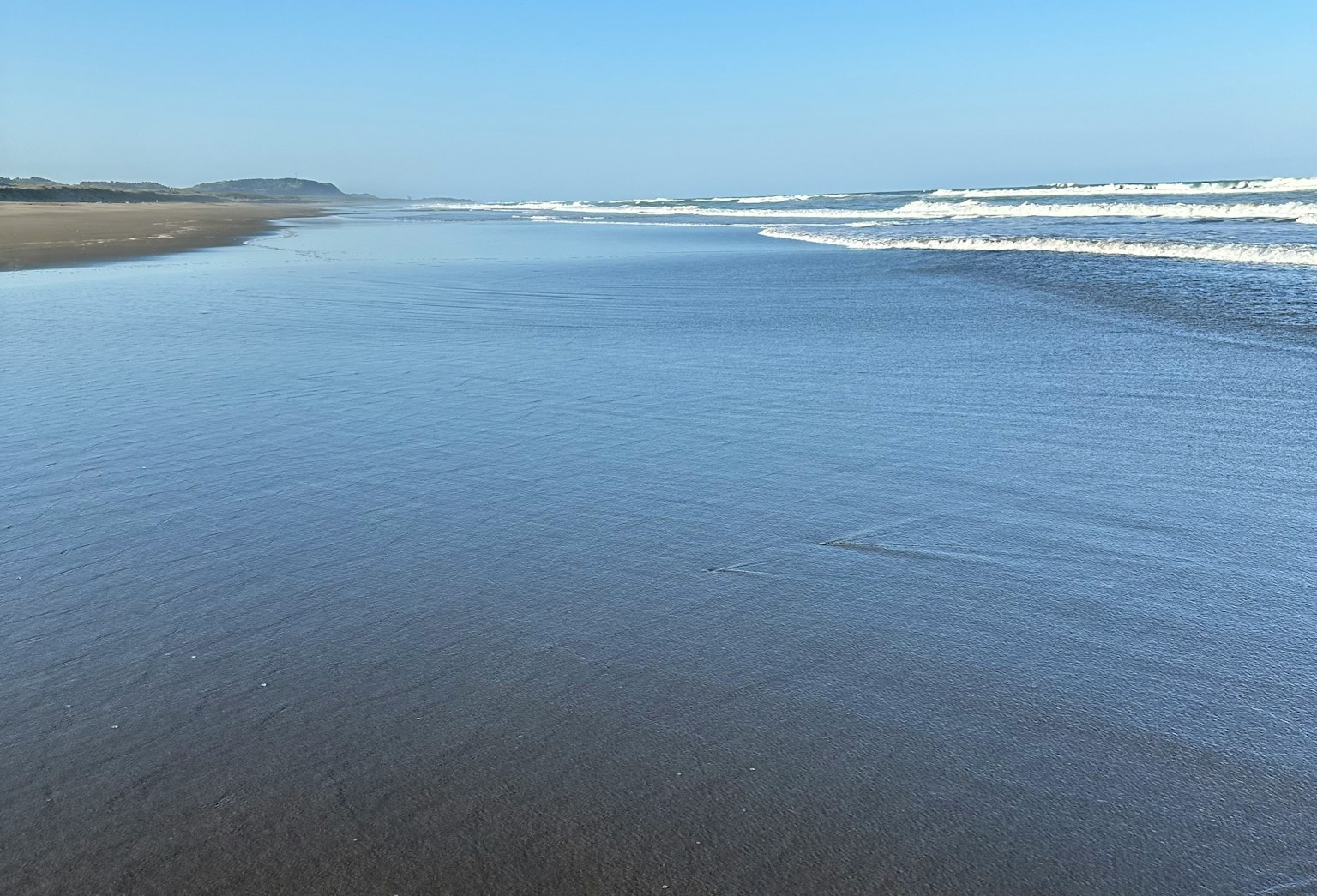 ทิวทัศน์ชายหาดที่เงียบสงบพร้อมมหาสมุทรสีน้ำเงินและคลื่นที่นุ่มนวล