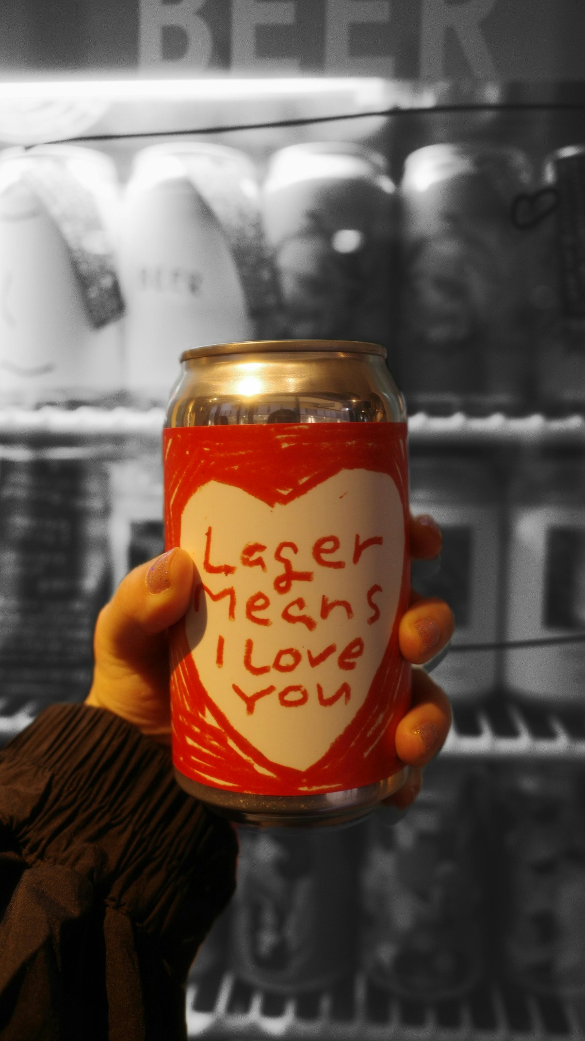 手に持ったビール缶と背景の樽