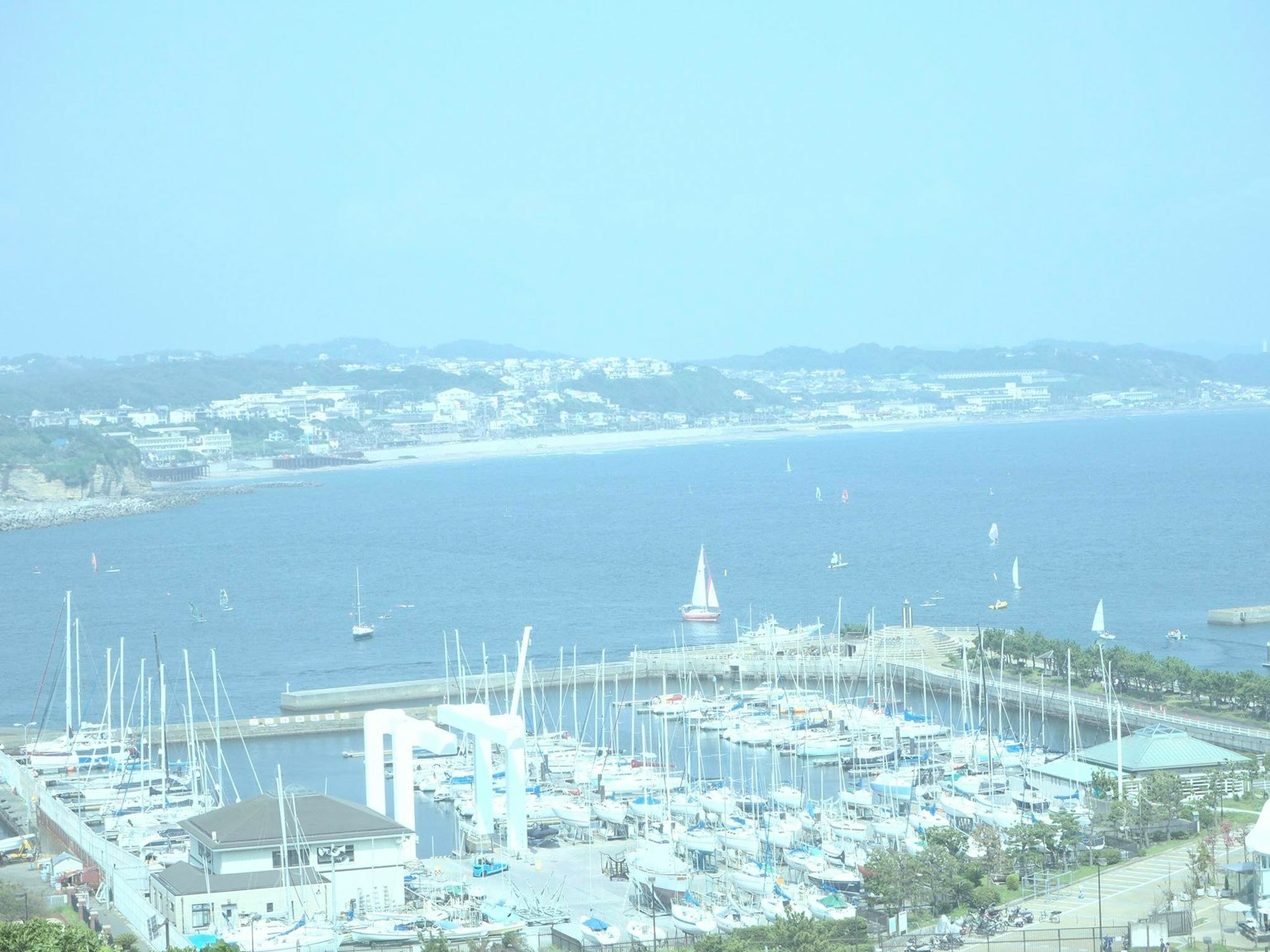 A coastal view featuring a marina with sailboats and distant land