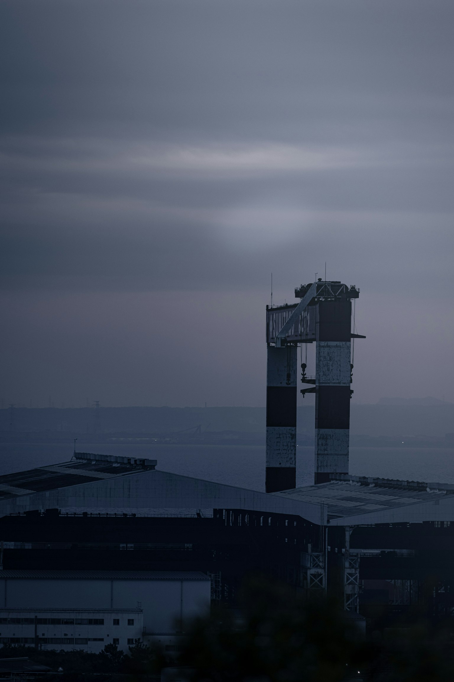 Silhouette von Fabrikschornsteinen und Gebäude unter einem dunklen Himmel