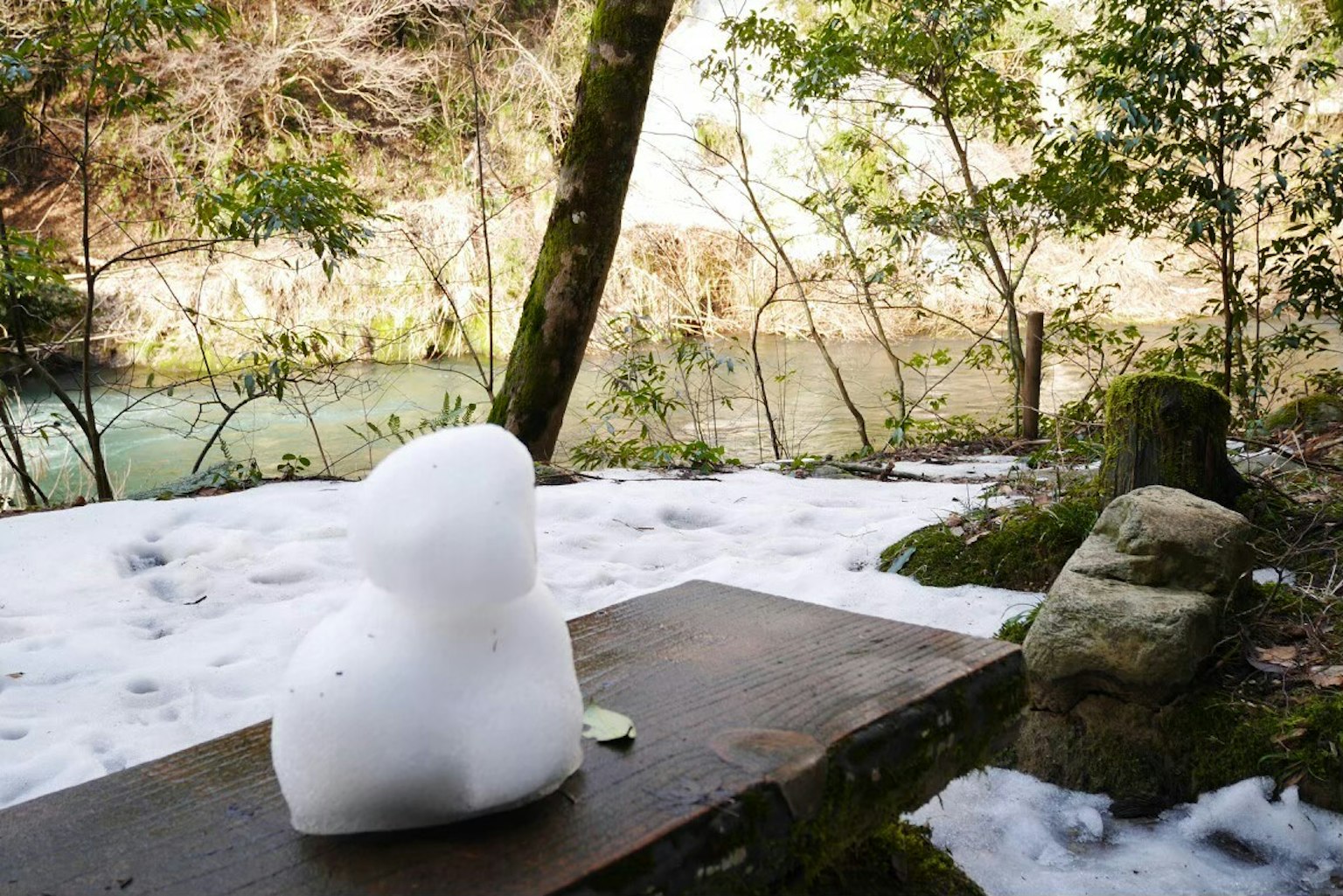 Scultura di neve accanto a un fiume in un paesaggio invernale