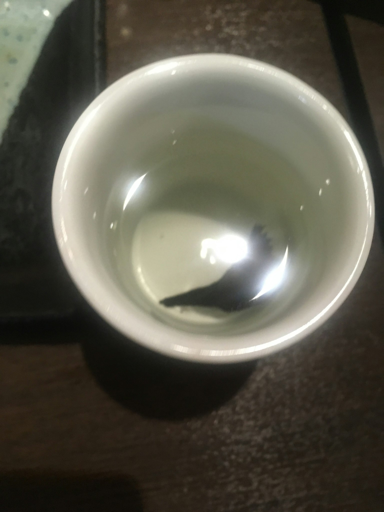 白色杯子裡有清澈的液體和一個黑色物體
