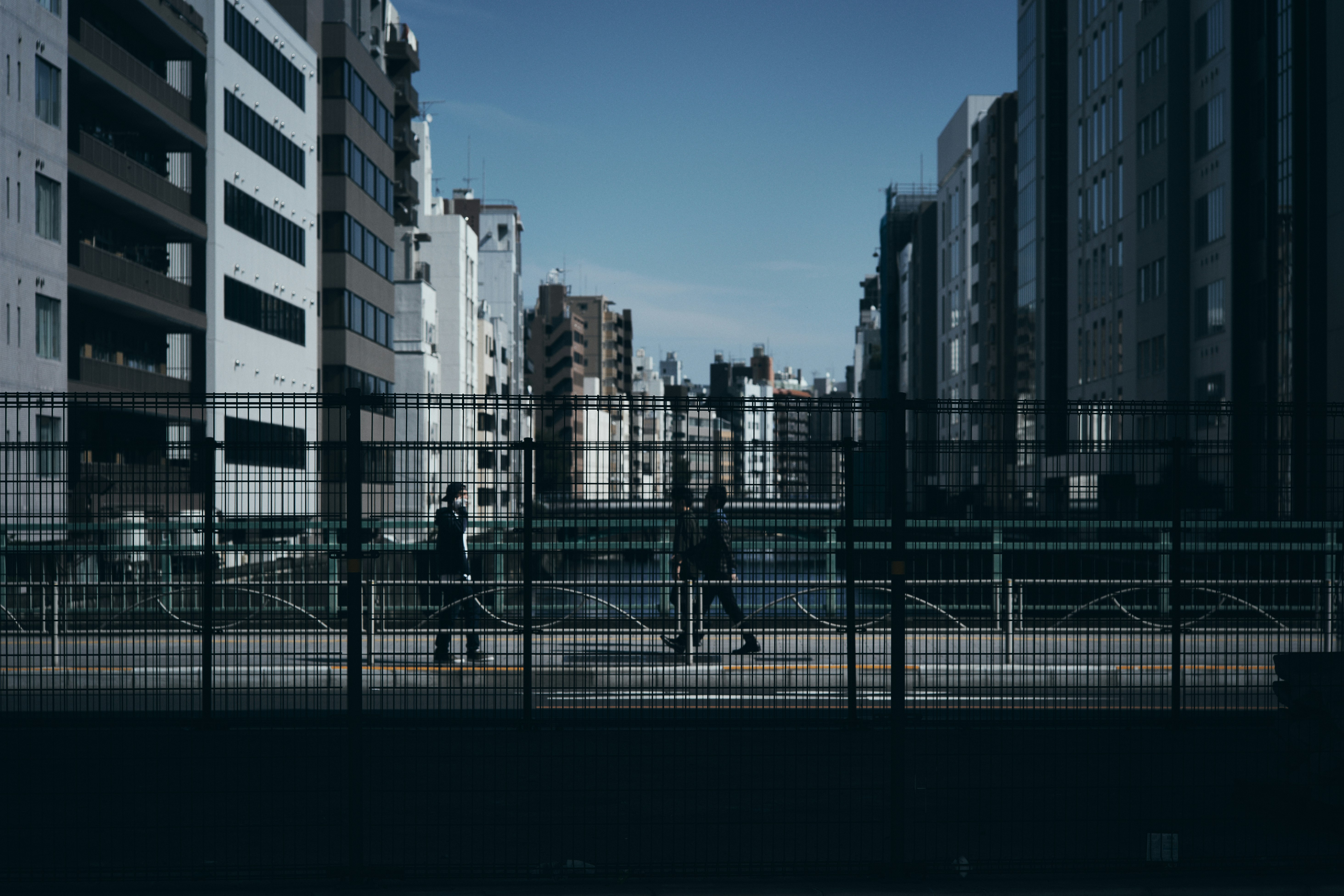 高層ビル群の間を走るフェンス越しの街並み