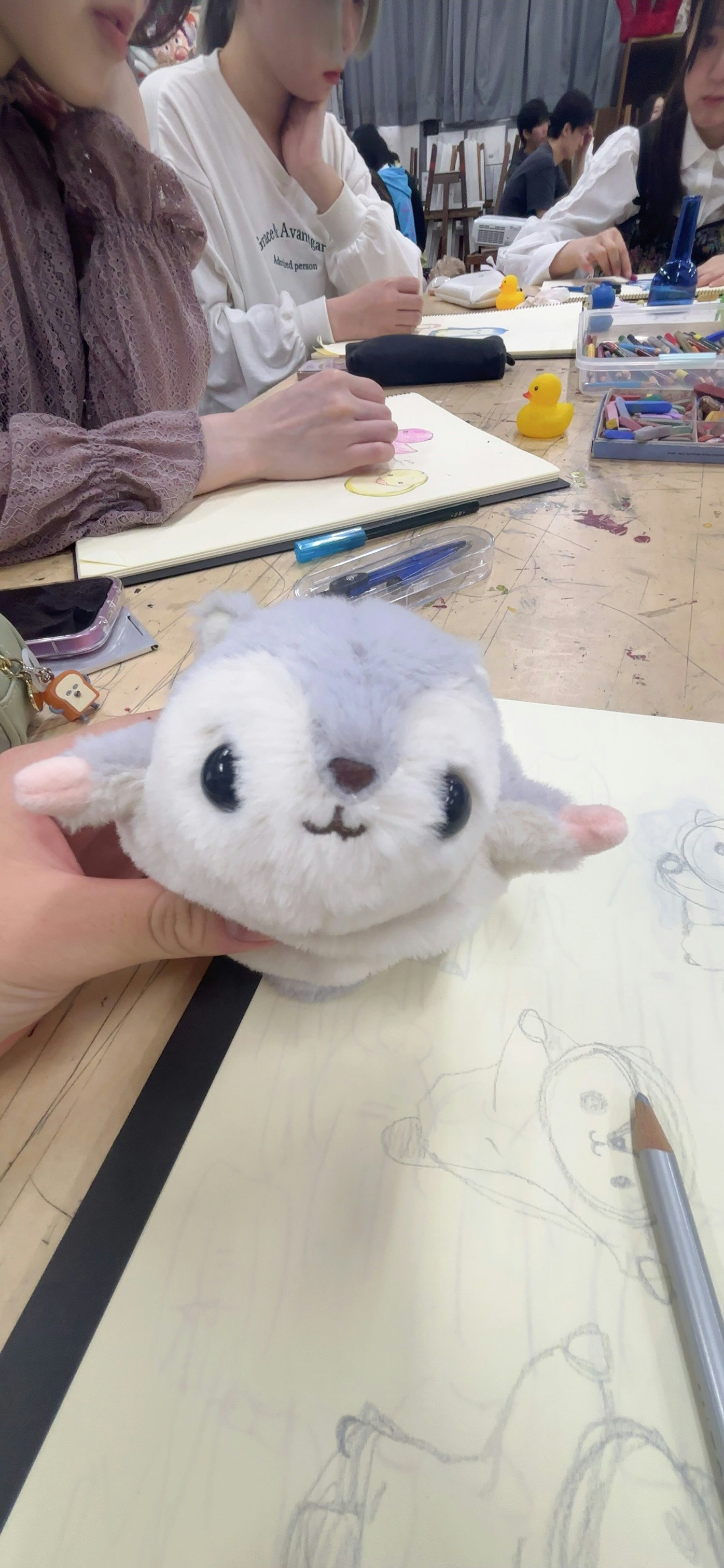机の上でぬいぐるみを抱えた参加者と手描きのイラスト