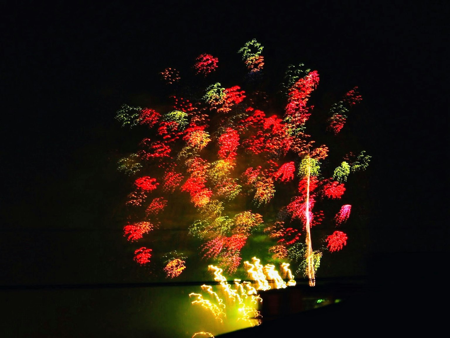 Spettacolo di fuochi d'artificio colorati nel cielo notturno con esplosioni rosse e verdi