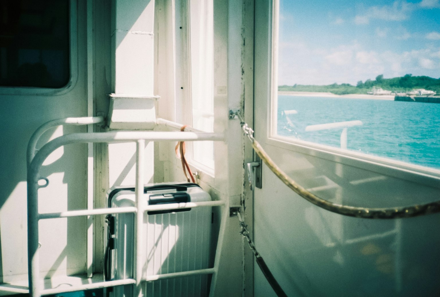 Vue de la mer depuis l'intérieur d'un bateau avec une porte et une rambarde