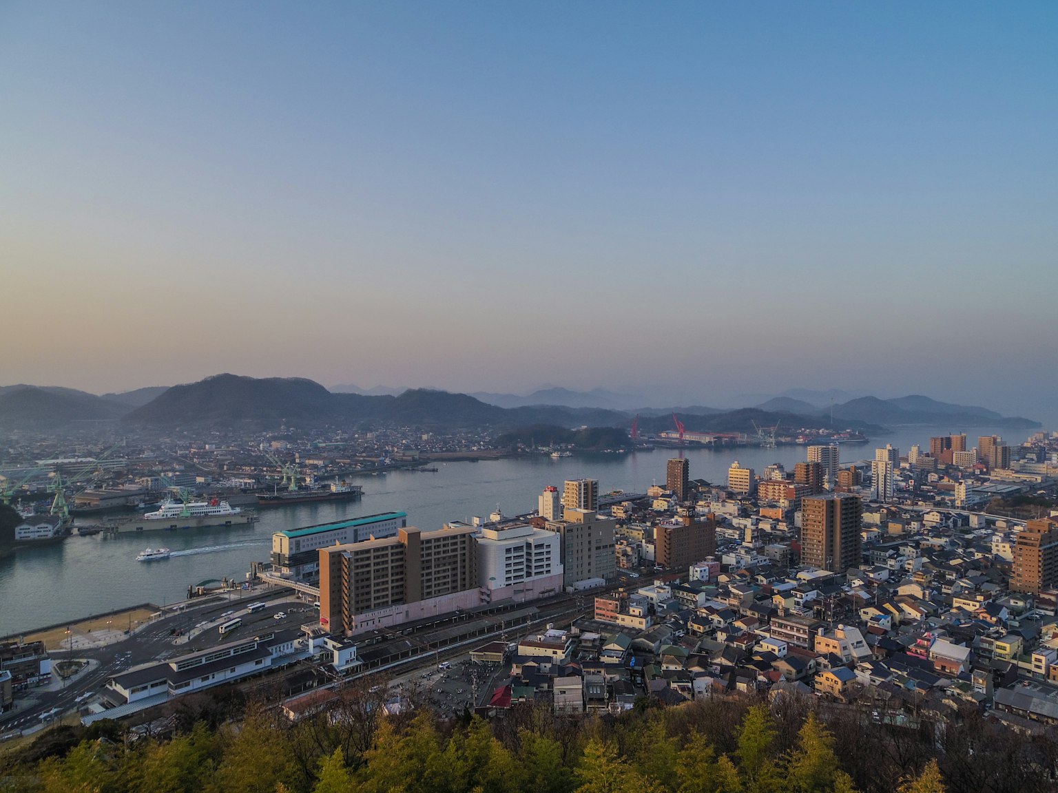Pemandangan panorama Nagasaki dengan pelabuhan dan kota saat matahari terbenam