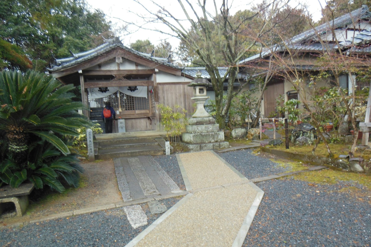 Arsitektur Jepang tradisional dengan patung batu dan vegetasi subur
