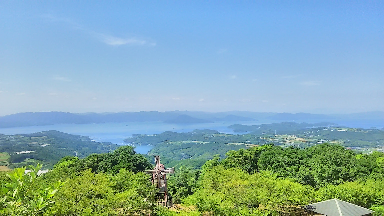 ทิวทัศน์ที่สวยงามของเนินเขาสีเขียวและทะเลสาบสีน้ำเงินใต้ท้องฟ้าที่แจ่มใส