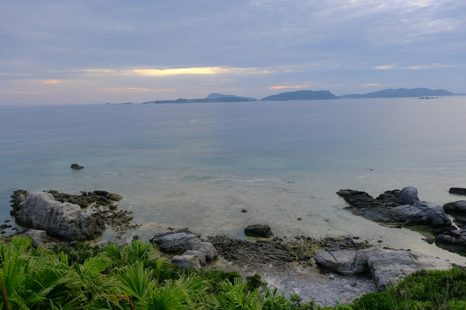 ทิวทัศน์ทะเลสงบที่มีเกาะห่างไกลและชายฝั่งหิน
