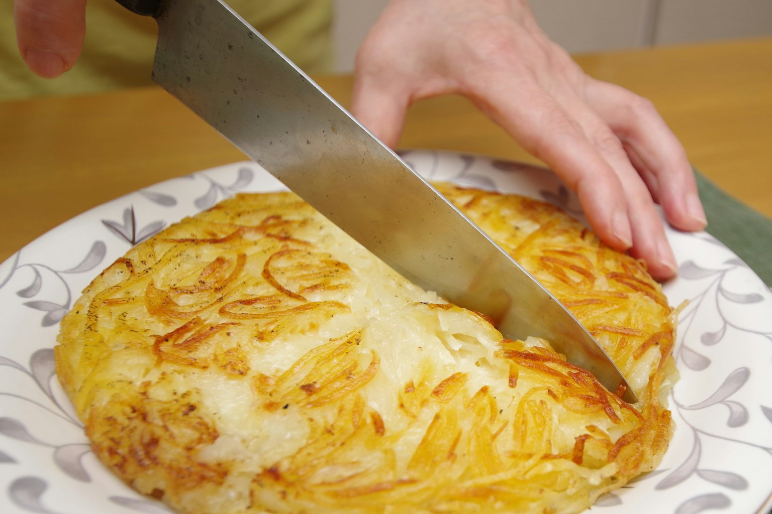 A hand cutting a tortilla on a decorative plate