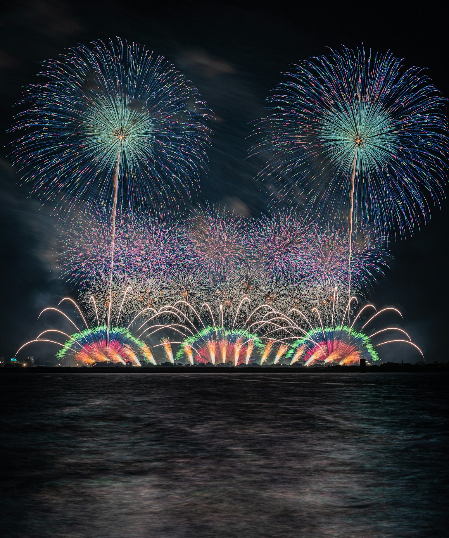 夜空中绽放的五彩烟花在水面上反射出美丽的景象