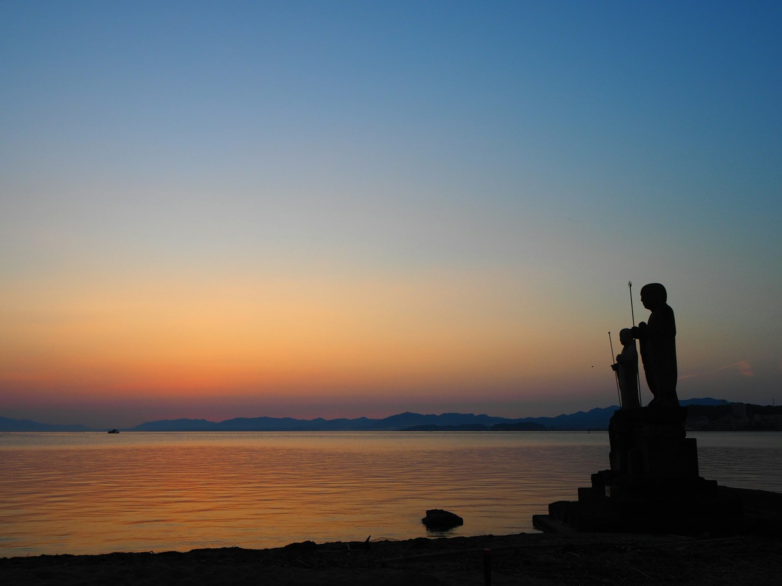 Silhouette di una scultura al mare al tramonto