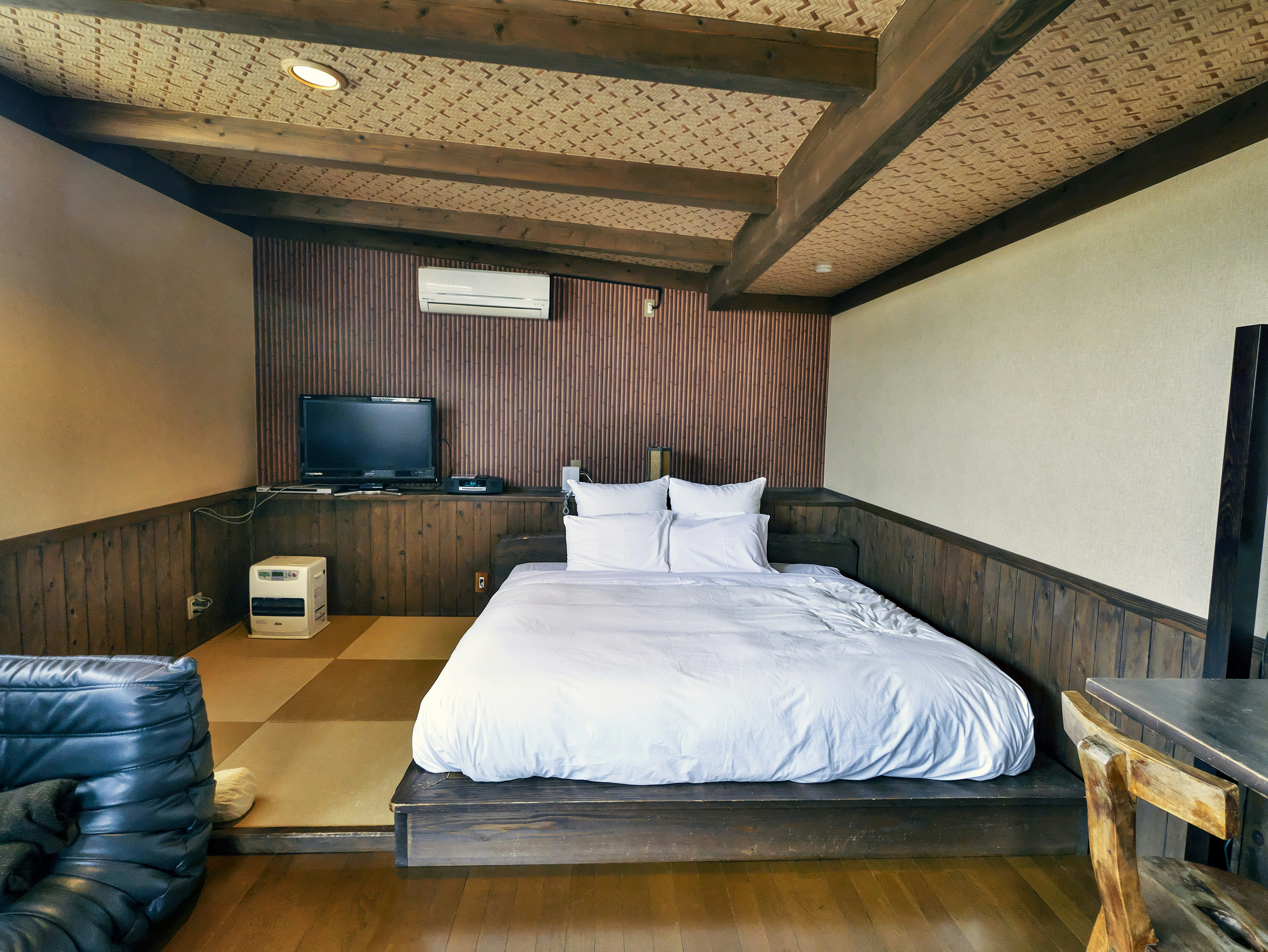 tempat tidur dan sprei di kamar tidur berdinding kayu
