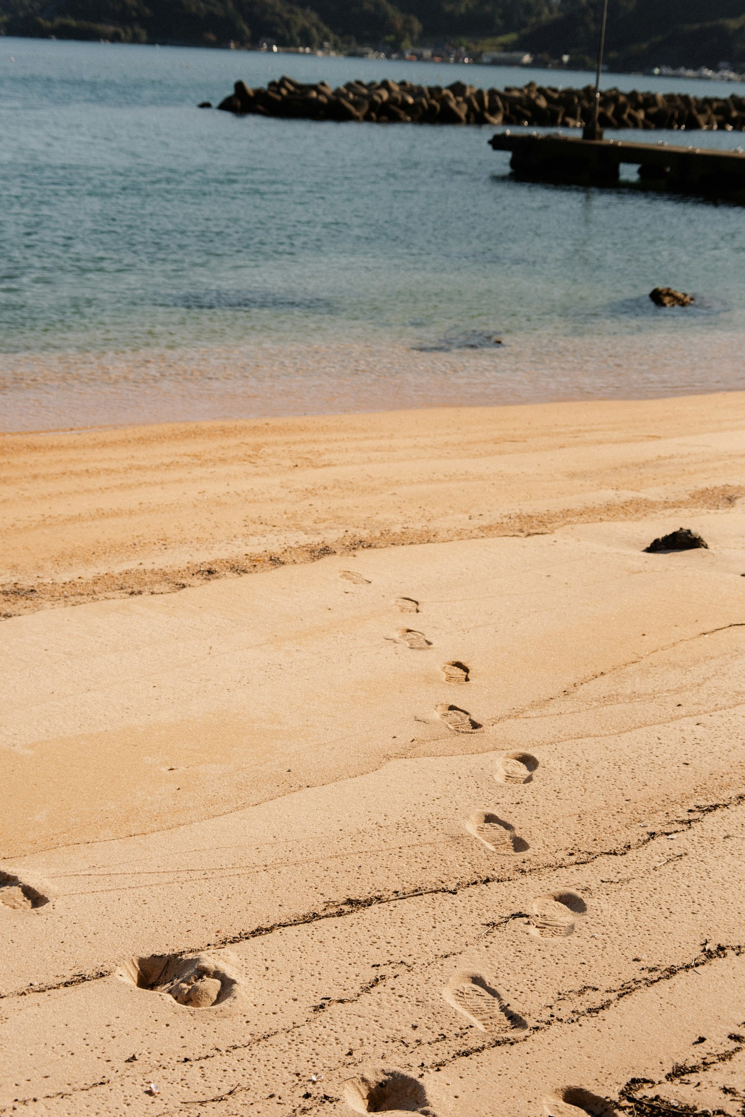 Des empreintes sur une plage de sable avec vue sur la mer calme