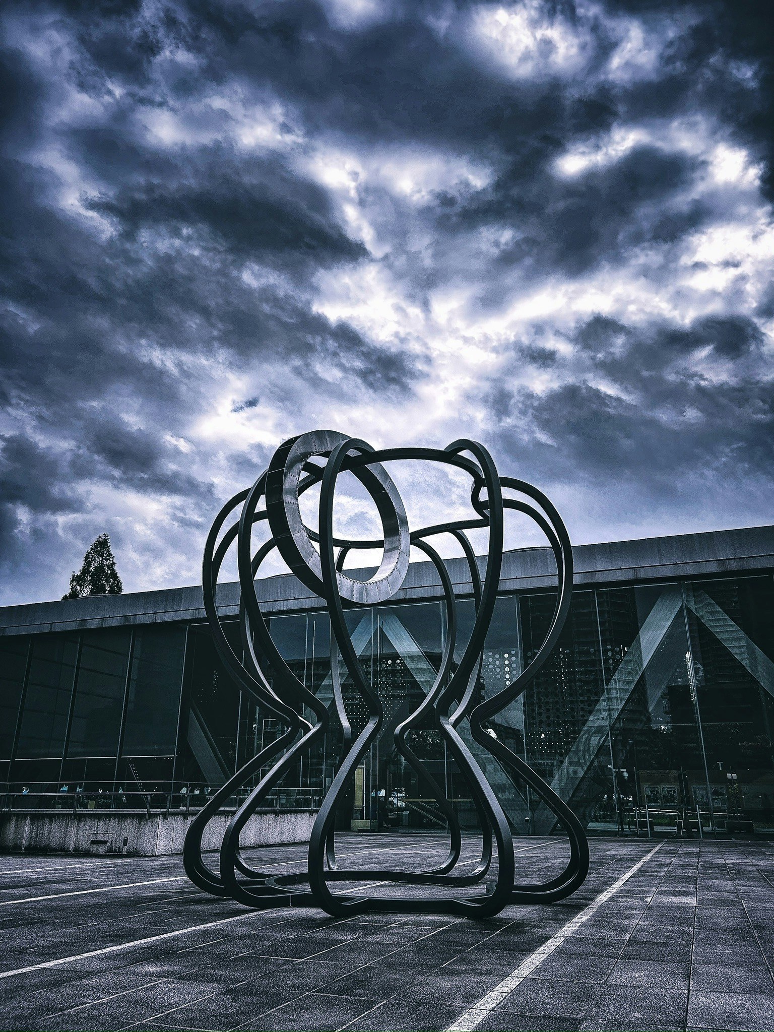 sculpture métallique abstraite en extérieur sous un ciel orageux