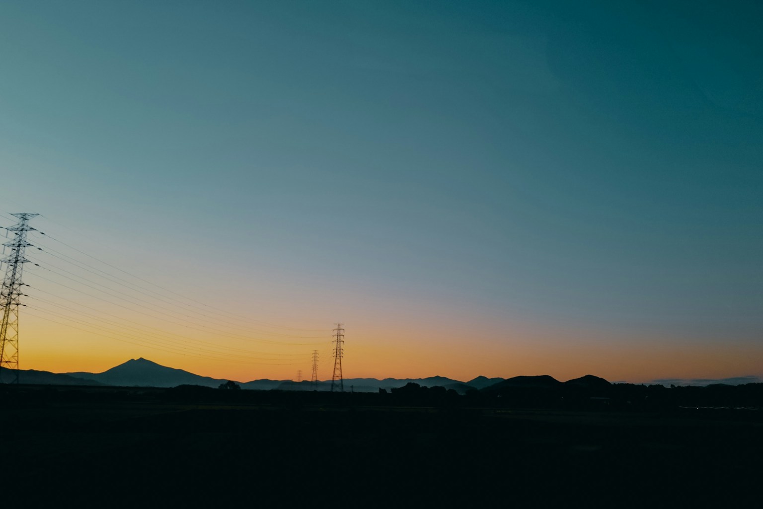 Eine ruhige Sonnenuntergangslandschaft mit Stromleitungen und Bergen