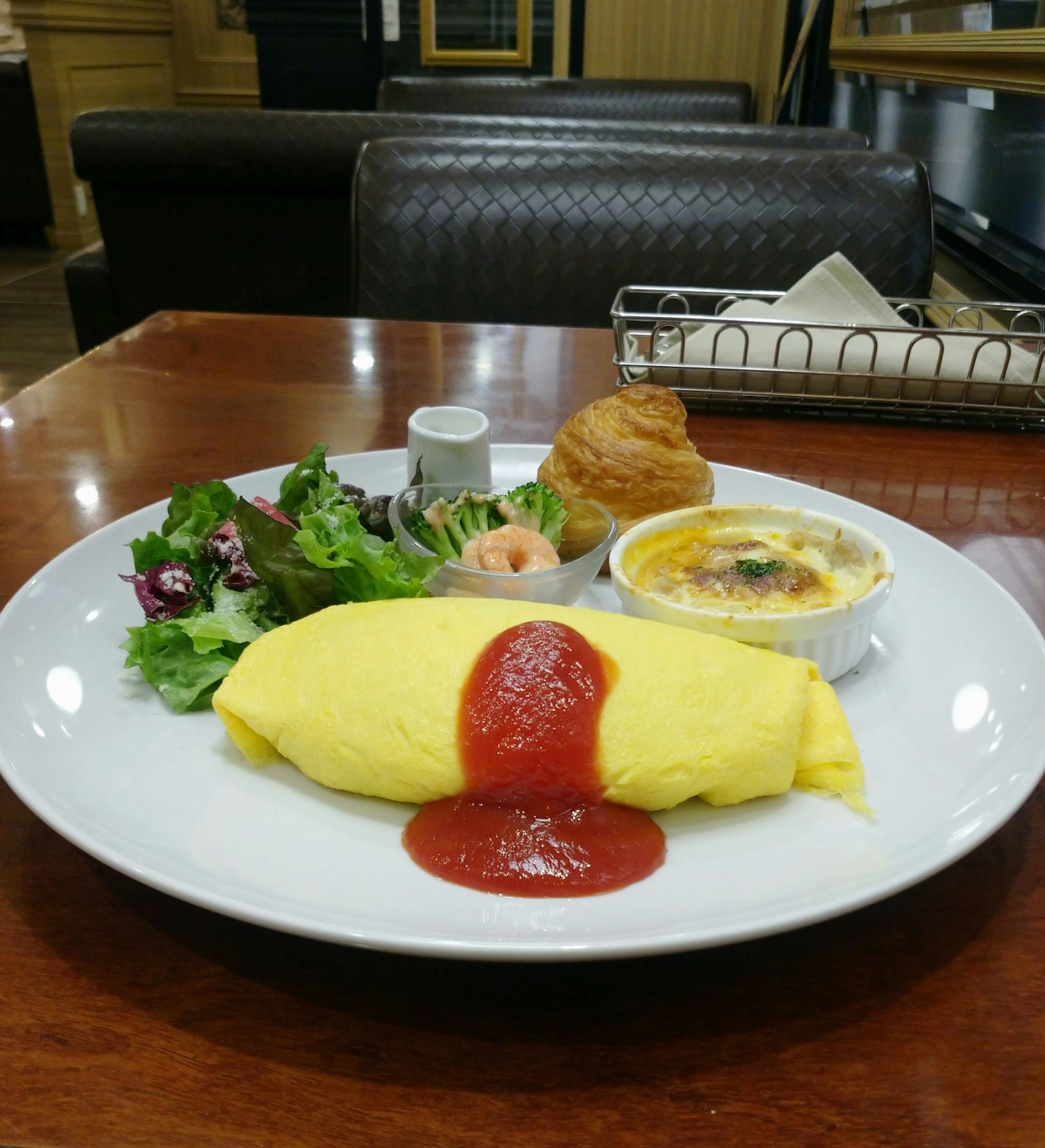 Assiette de petit-déjeuner avec une omelette jaune garnie de ketchup accompagnée de salade et de crème brûlée