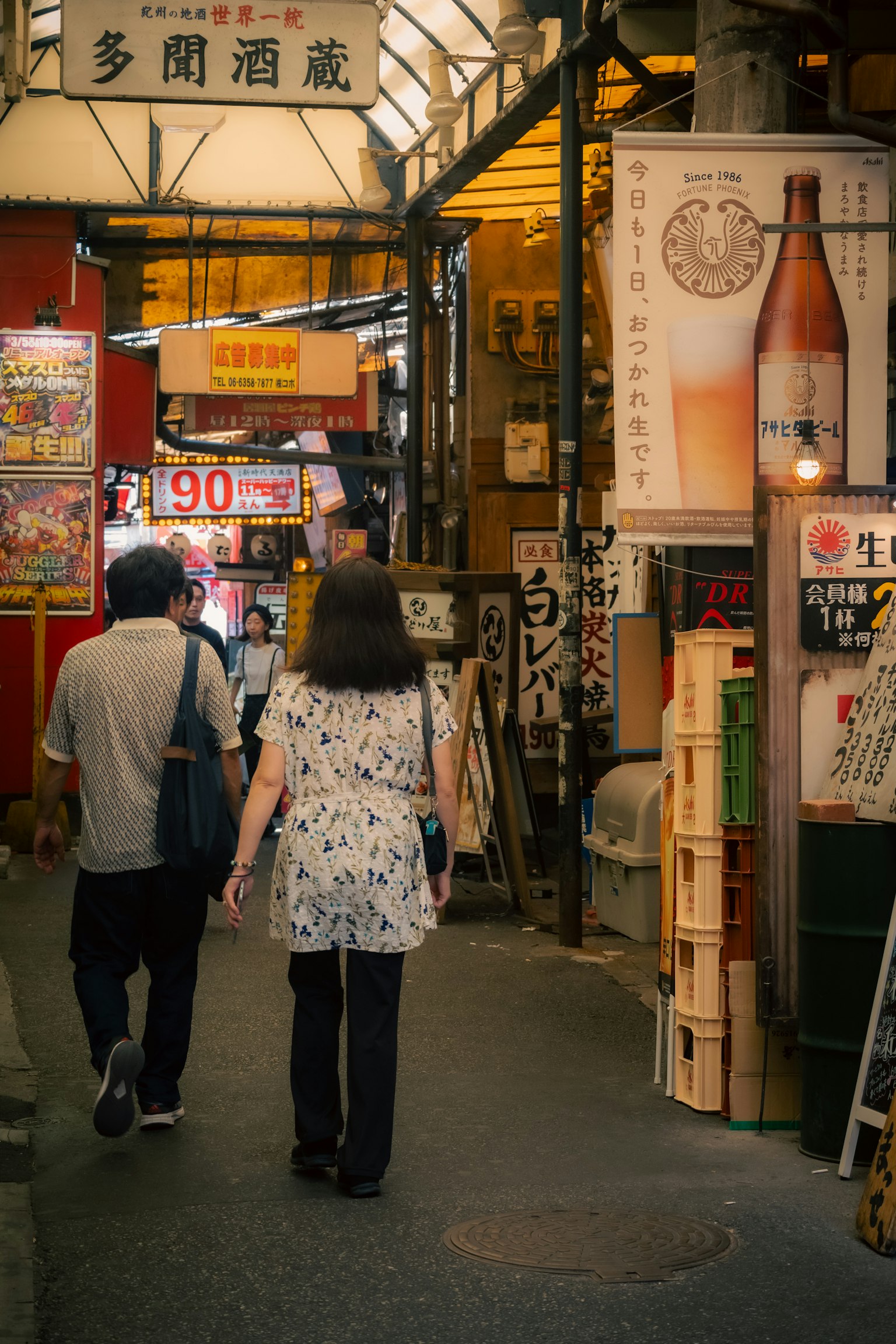 People walking in a bustling shopping street with sake advertisements