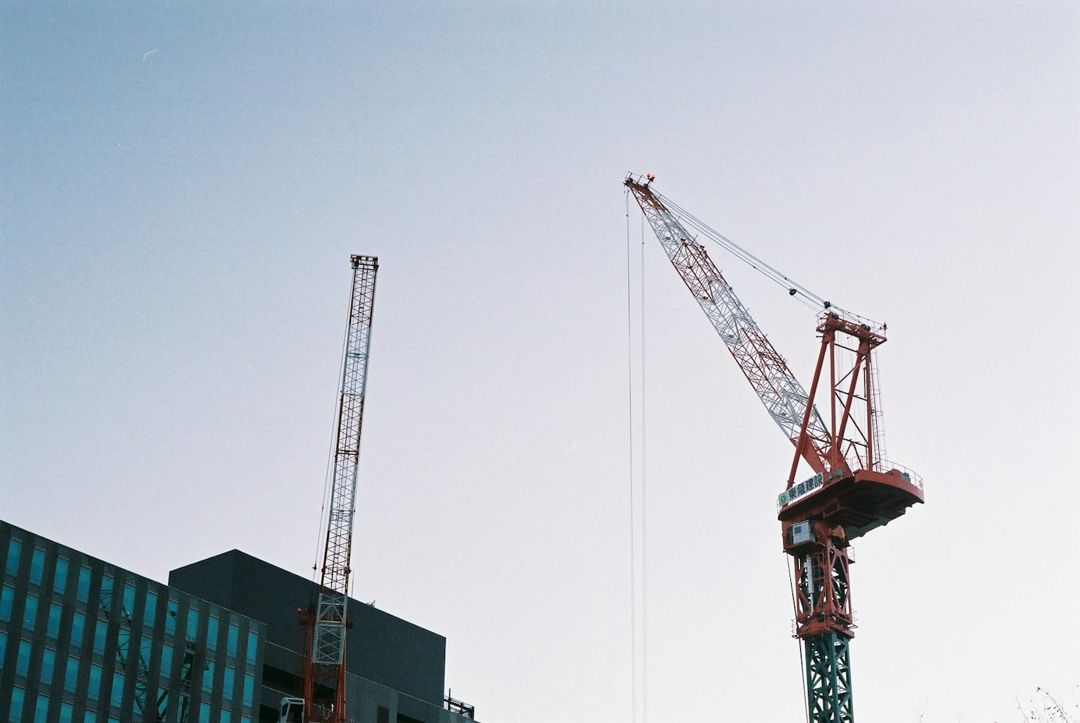 Grues contre un ciel bleu avec une partie d'un bâtiment