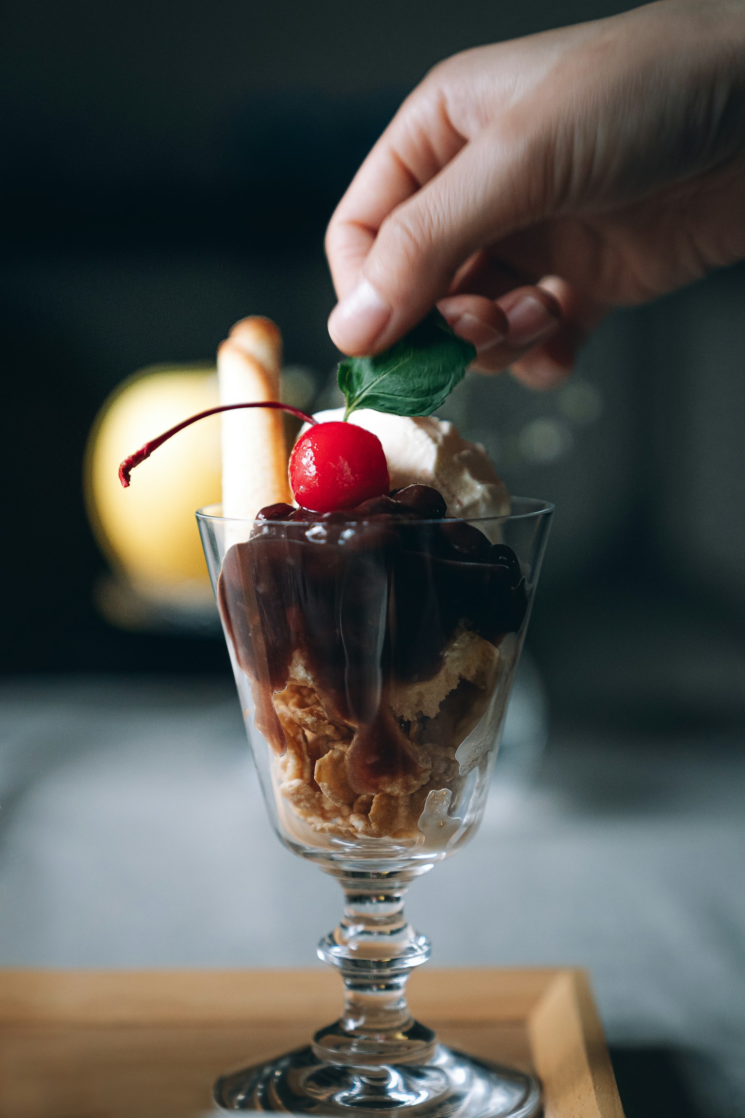 Hand adding topping to an ice cream parfait