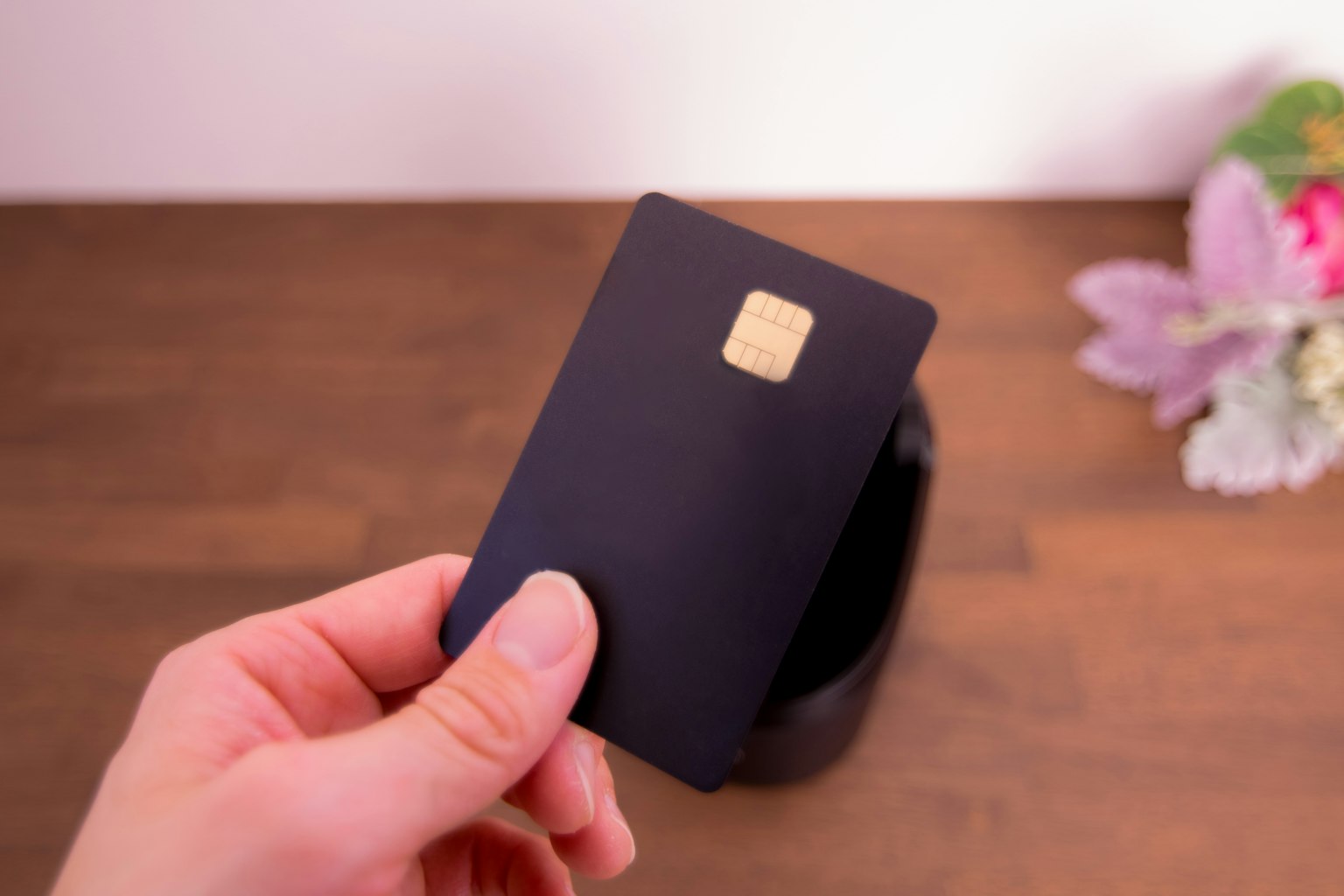 Une carte noire tenue à la main avec un fond fleuri