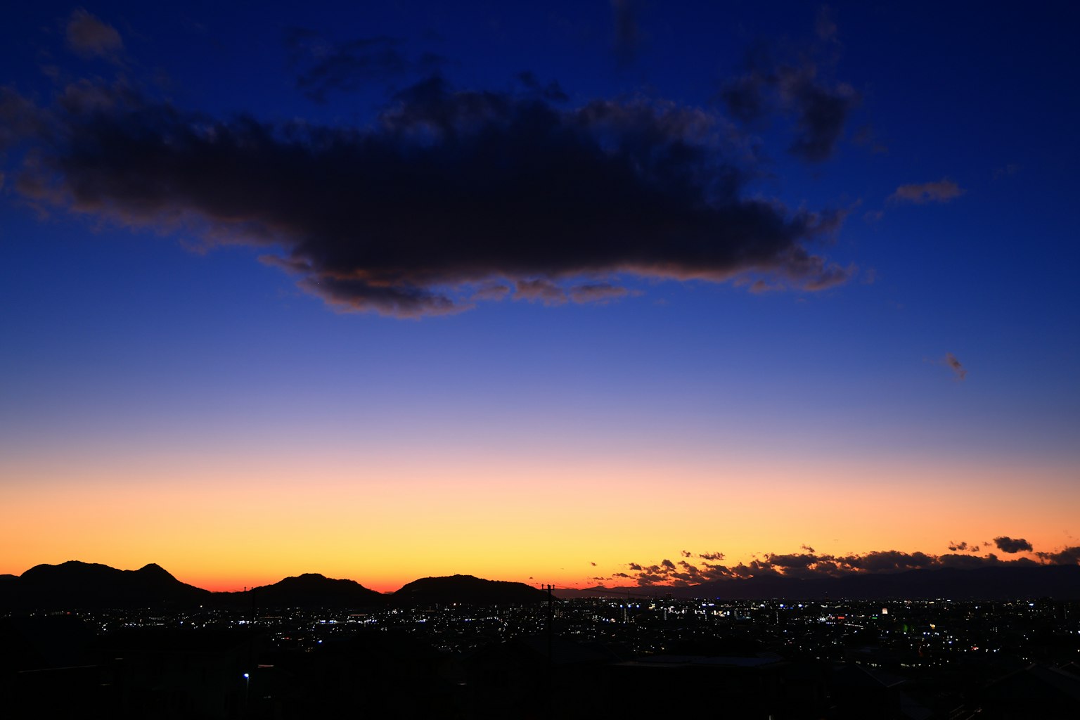 夕焼けの空に浮かぶ雲と山のシルエット