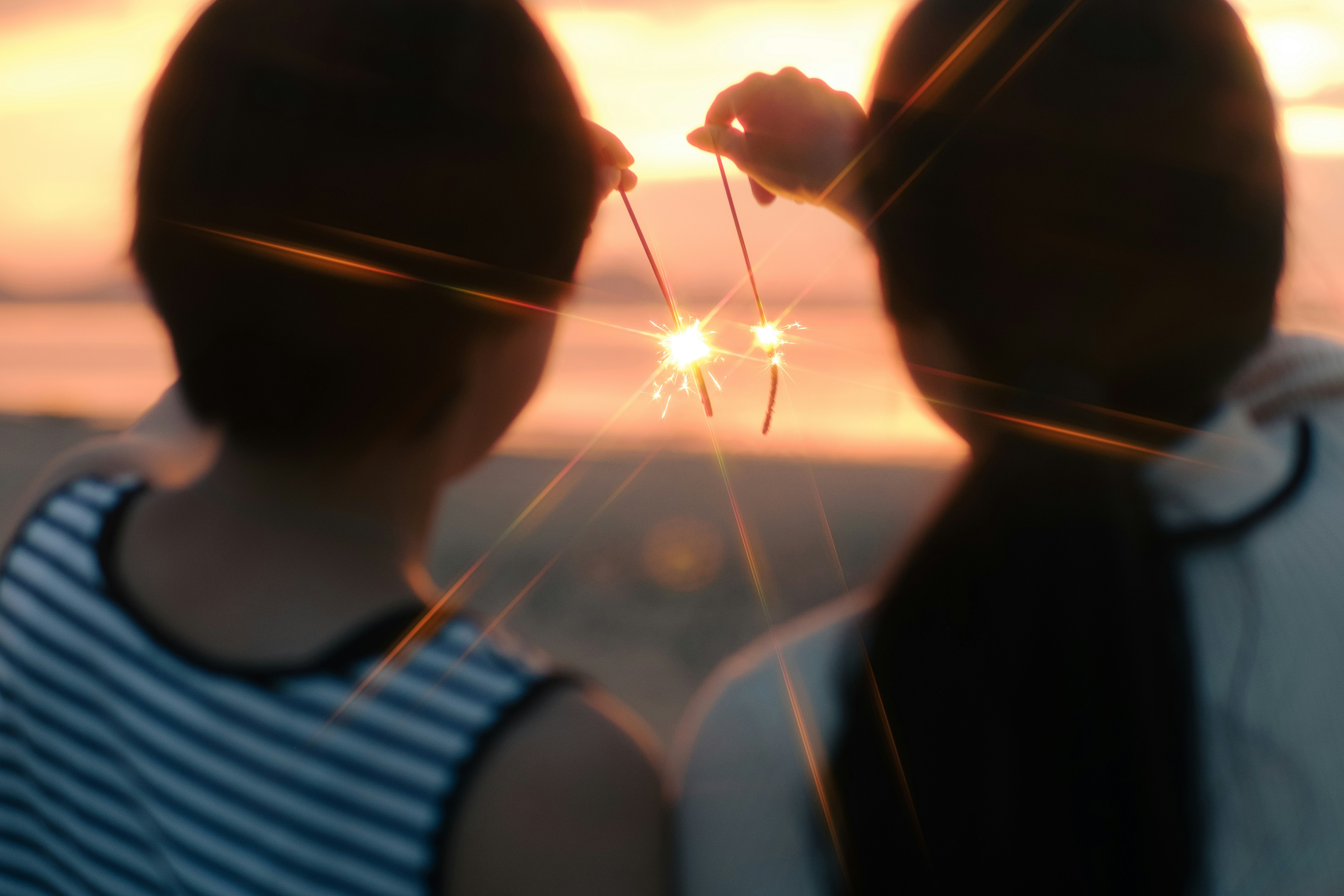夕日に照らされた子どもたちの後ろ姿ときらめく花火
