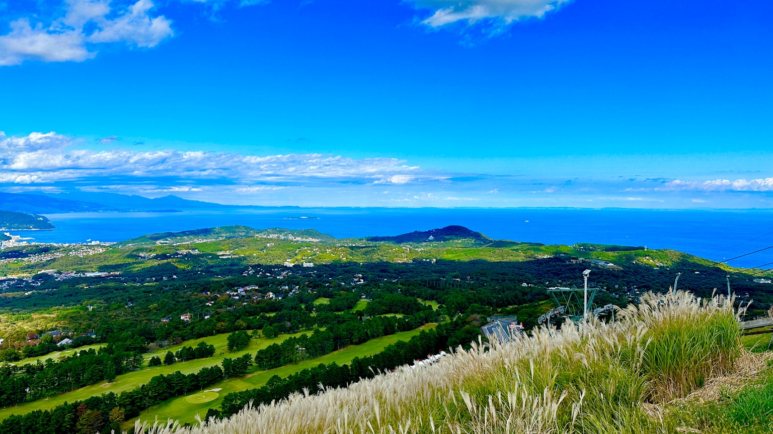 Pemandangan indah dengan langit biru dan laut bukit hijau dan padang