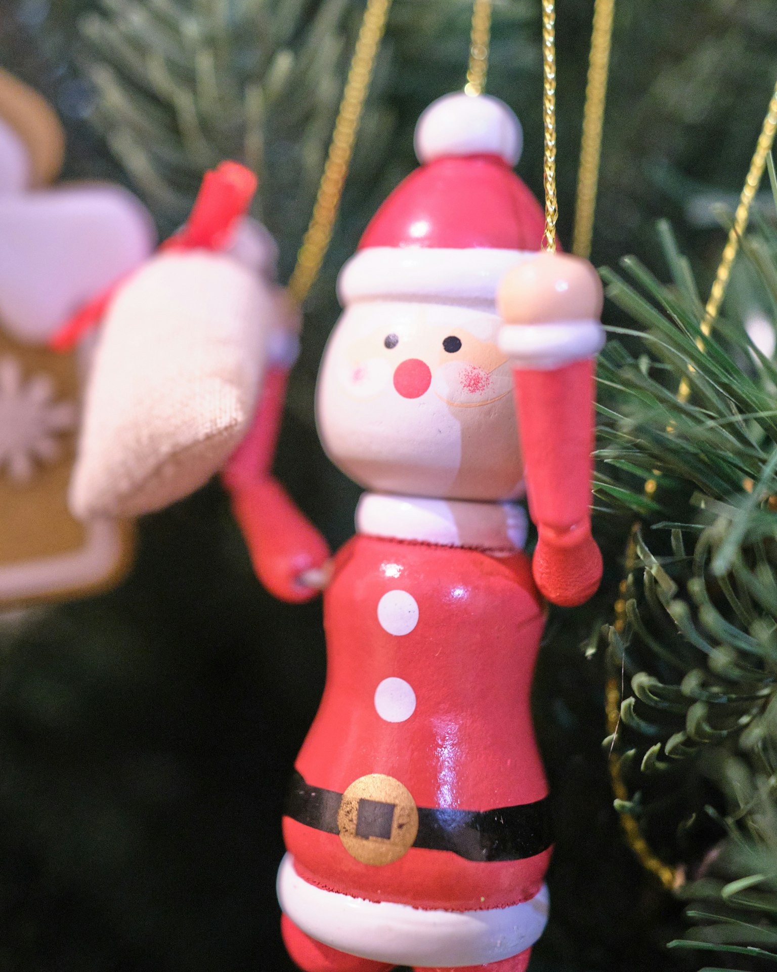 Santa Claus ornament in red outfit hanging on a Christmas tree