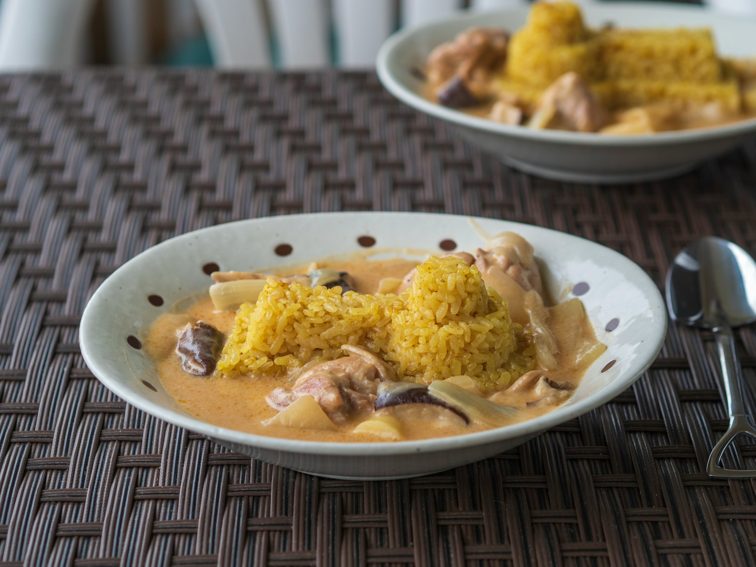 Plato de arroz amarillo con salsa cremosa y pollo servido en una mesa trenzada
