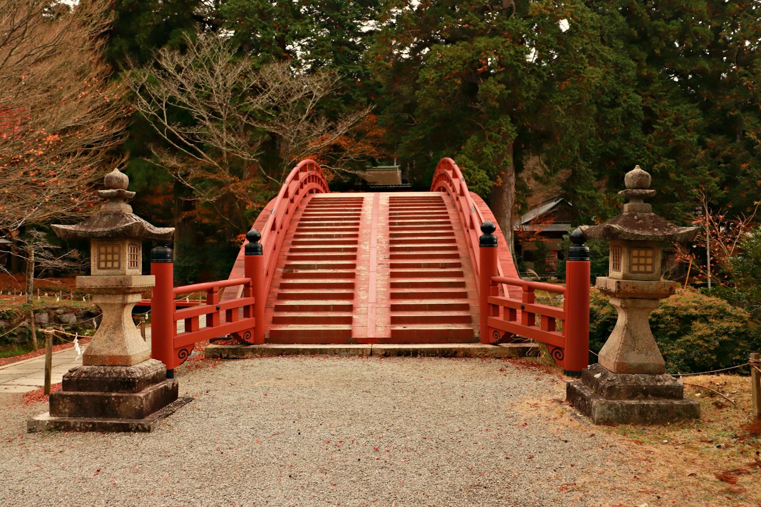 Un bel ponte rosso con lanterne di pietra ai lati in un giardino