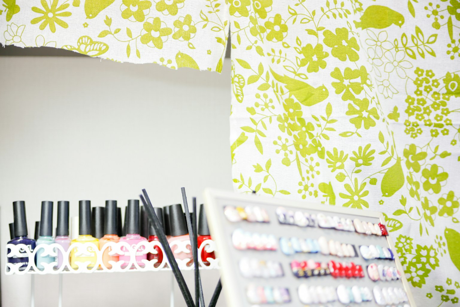 Botellas de esmalte de uñas con una pared de fondo con patrón floral