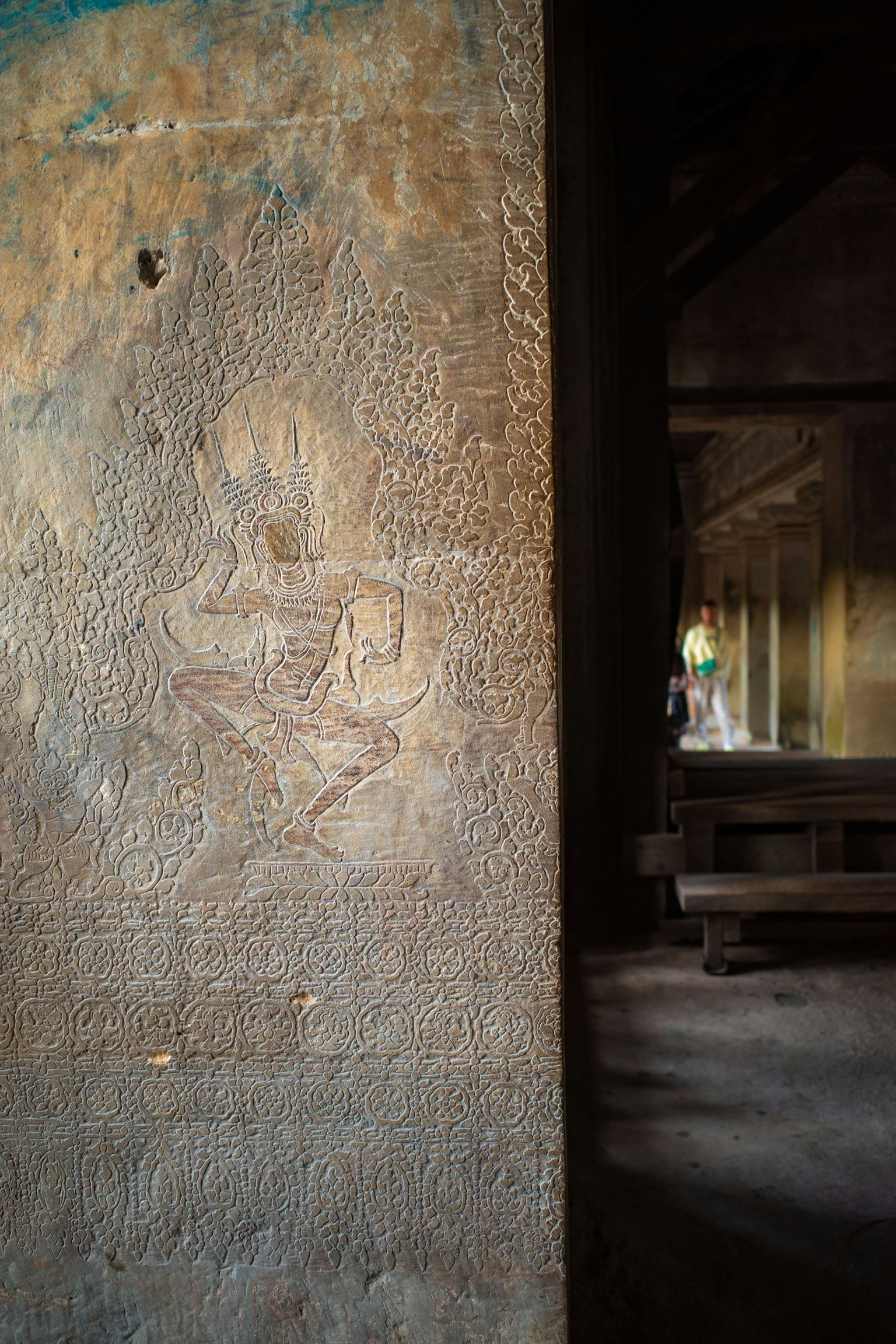 Interior of a temple featuring wall carvings and a figure in the background