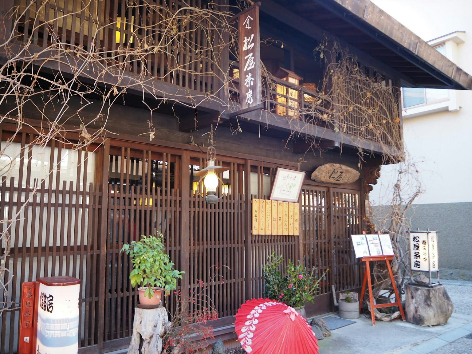Extérieur d'un bâtiment traditionnel japonais avec treillis en bois plantes vertes parapluie rouge