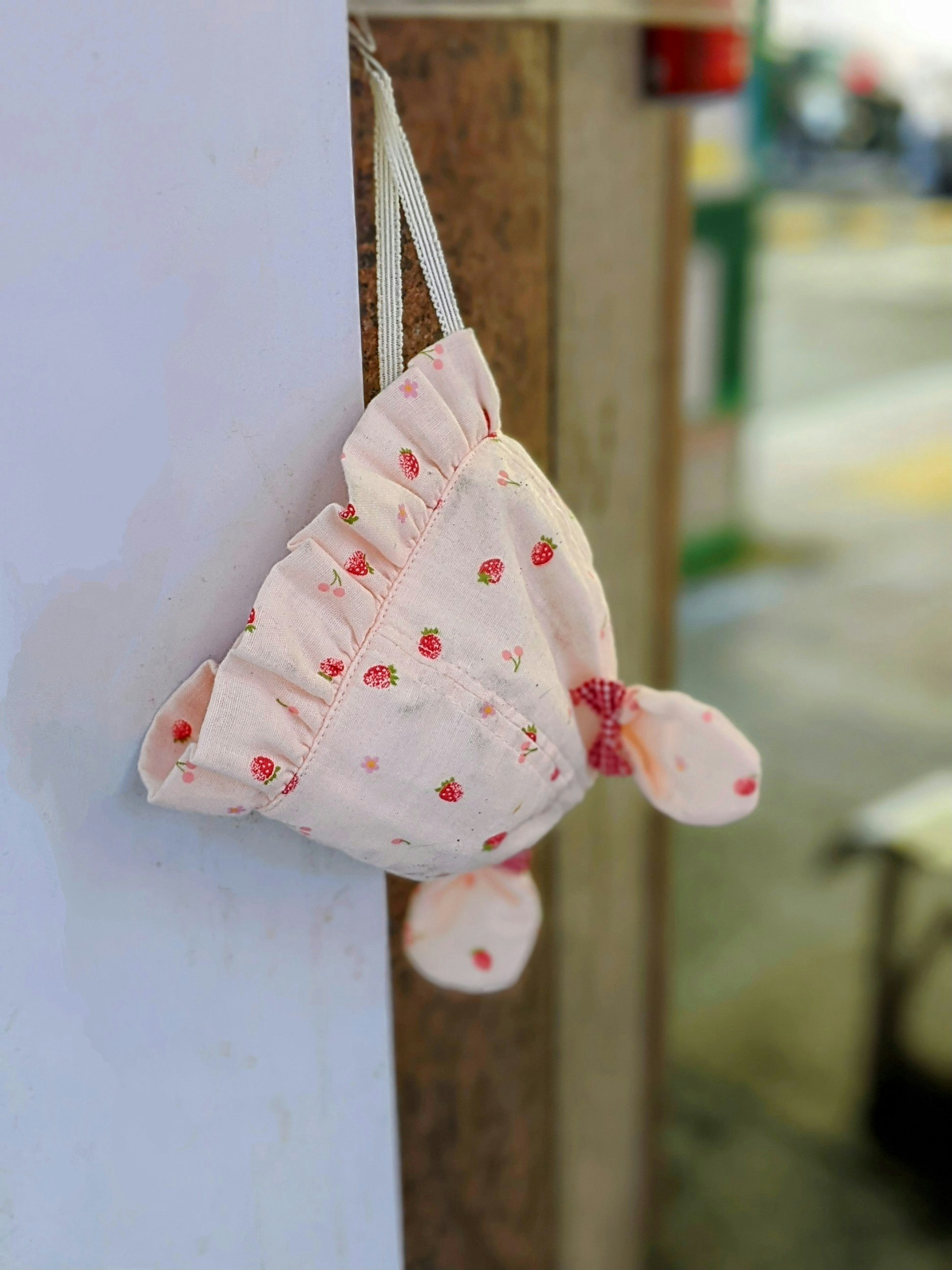 壁に掛かった赤ちゃん用の帽子と小さな袋