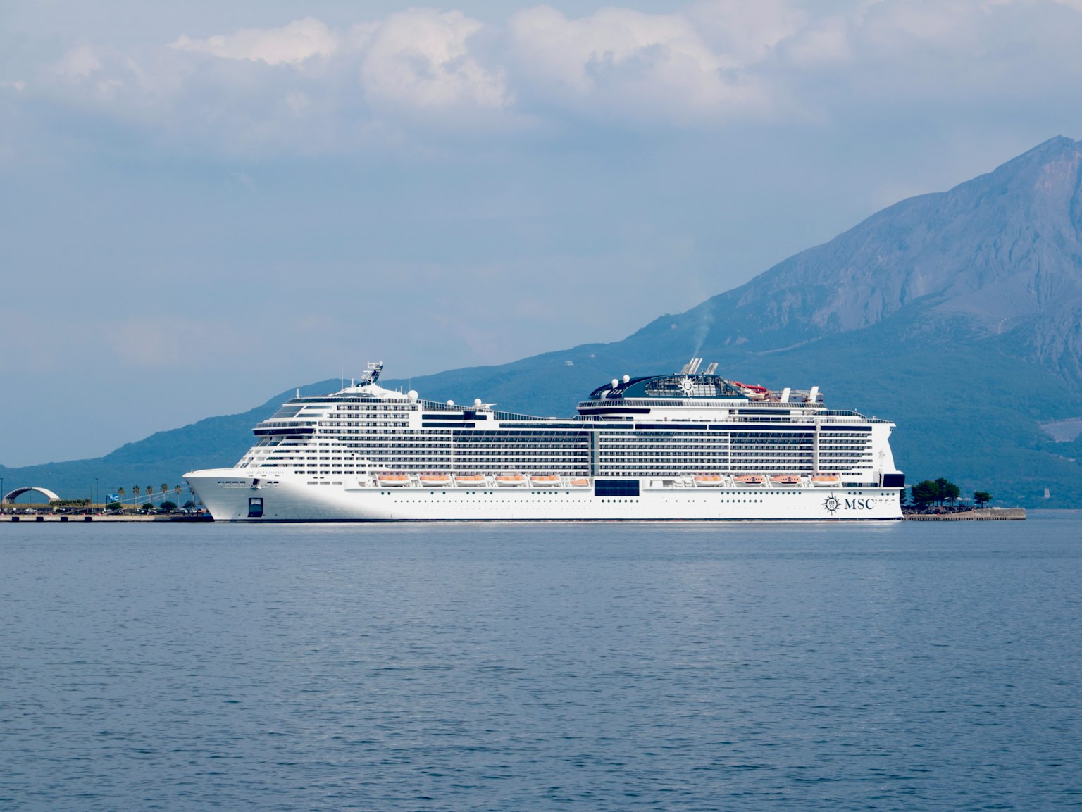 Un grand navire de croisière naviguant sur des eaux calmes avec des montagnes en arrière-plan