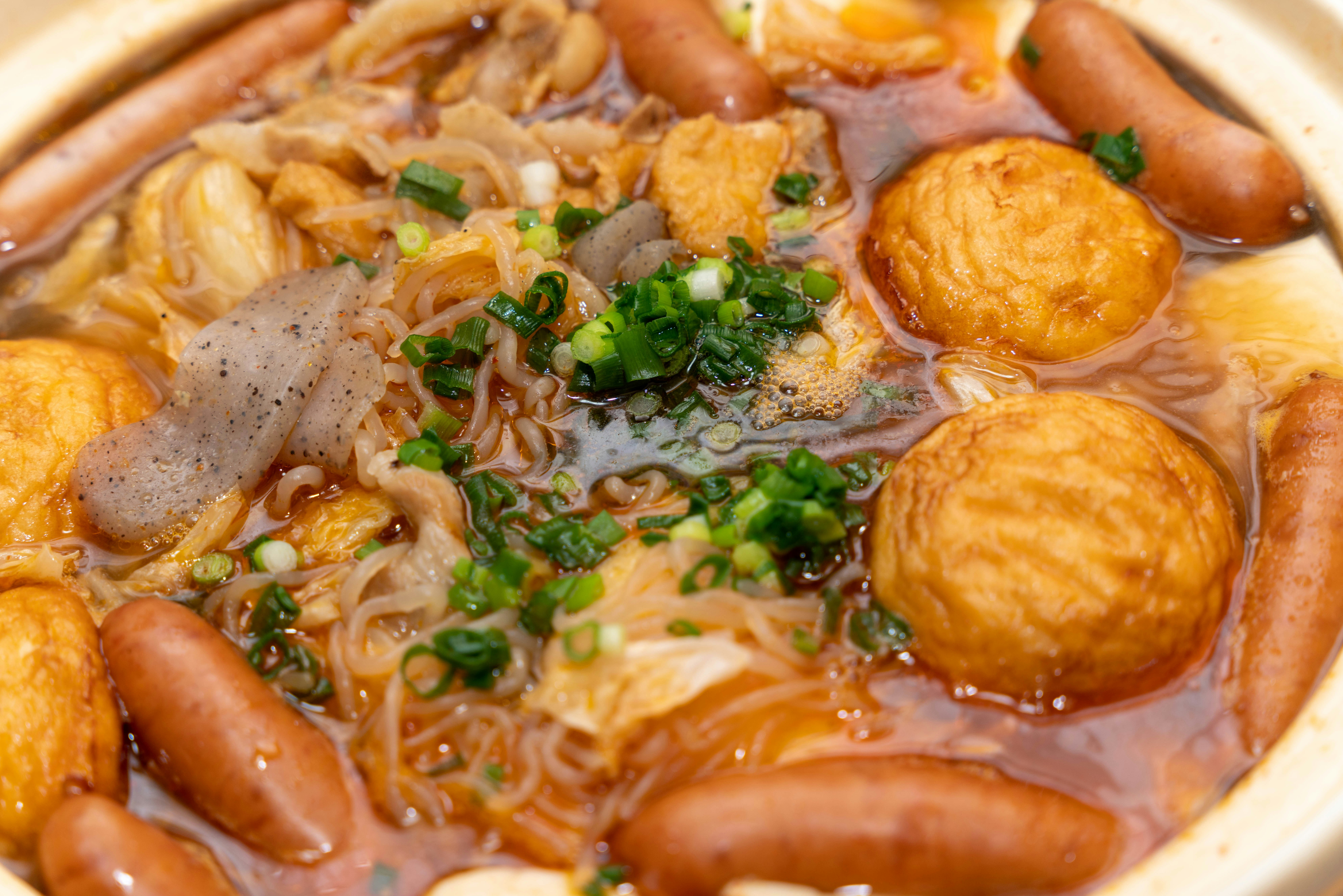 Piatto di pentola calda con polpette di pesce e salsicce in un brodo saporito
